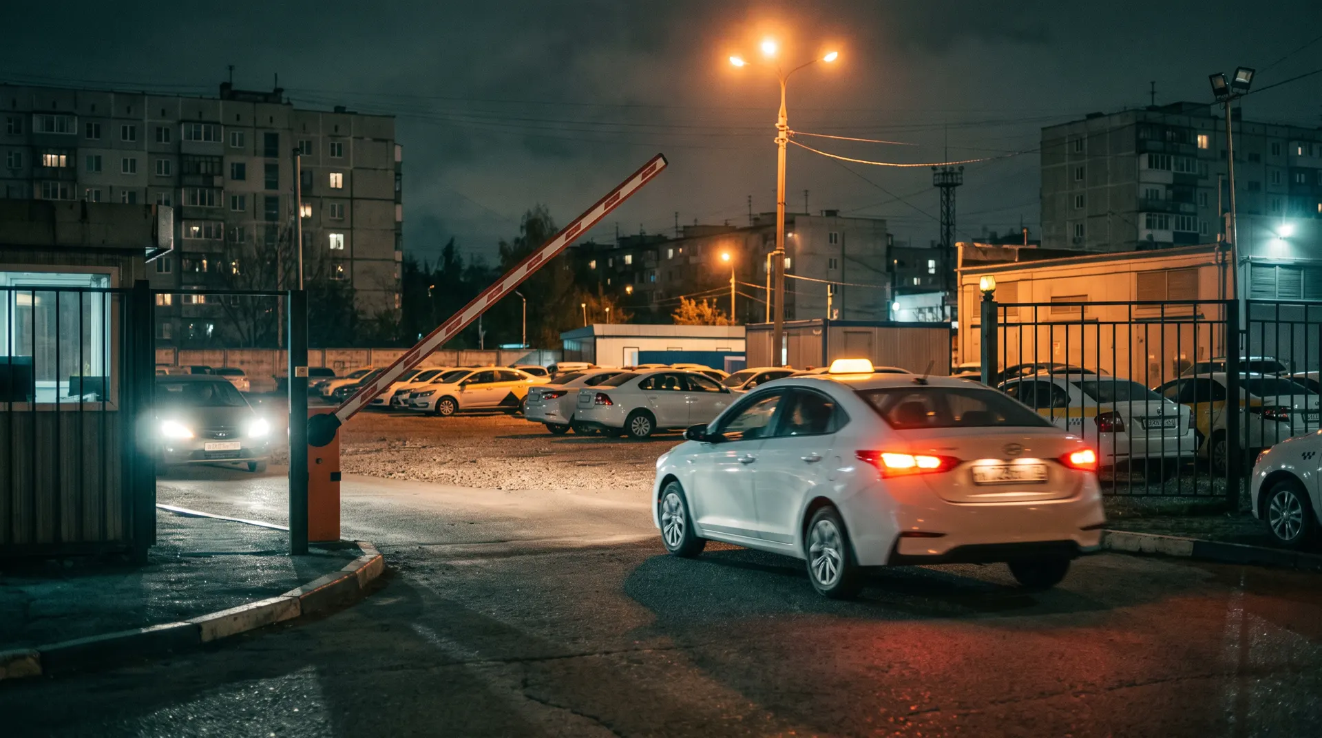 Один автомобиль выезжает из ворот таксопарка, другой ждёт въезда